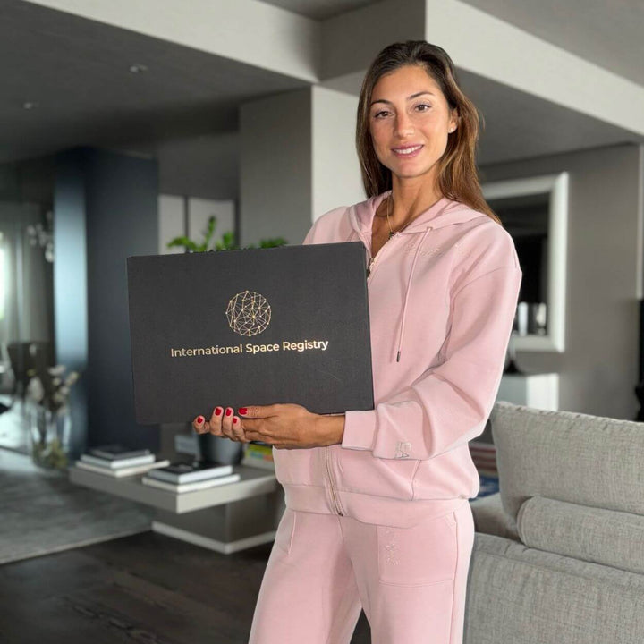 Happy customer holding the International Space Registry presentation folder with gold logo